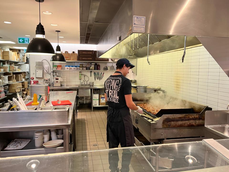 chipotle worker cooking meat in the kitchen