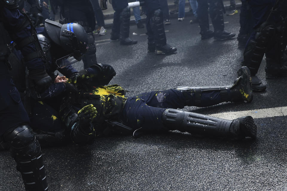 A riot police officer is lying on the pavement during a demonstration in Paris, Monday, May 1, 2023. Across France, thousands marched in what unions hope are the country's biggest May Day demonstrations in years, mobilized against President Emmanuel Macron's recent move to raise the retirement age from 62 to 64. (AP Photo/Aurelien Morissard)