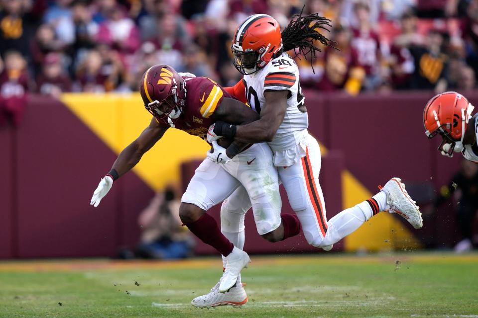 Cleveland Browns defensive end Jadeveon Clowney (90) tackles Washington Commanders running back Brian Robinson Jr. (8) on Jan. 1, 2023.