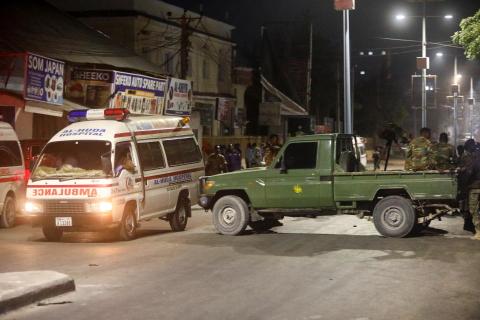 Somali security officers secure the scene of a car bomb explosion as paramedics await to rescue the injured in the Kilometre 4 area of Mogadishu, Somalia.