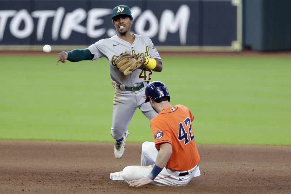 Oakland Athletics second baseman Tony Kemp, top, turns a double play over Houston Astros' Kyle Tucker, bottom, during the fifth inning of the first baseball game of a doubleheader Saturday, Aug. 29, 2020, in Houston. All players and managers are wearing No. 42 as a tribute to baseball great Jackie Robinson. (AP Photo/Michael Wyke)