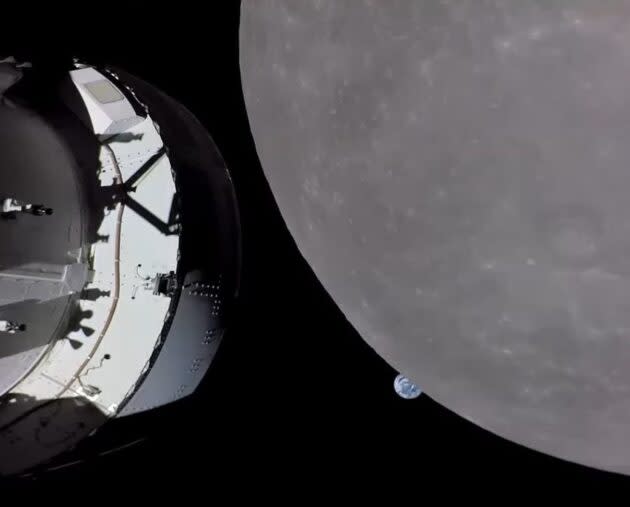 A view captured by a camera on one of Orion’s solar array wings shows Earth setting beneath the moon’s horizon. A portion of the Orion capsule is in the foreground at left. (NASA Photo)