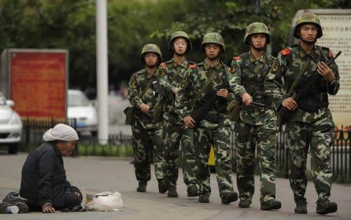 A Muslim Uighur woman begs as armed Chinese paramilitary policemen along a street in Urumqi, capital of the tense Xinjiang region. A deadly weekend attack in the province was masterminded by "terrorists" trained in Pakistan, the local government said Monday