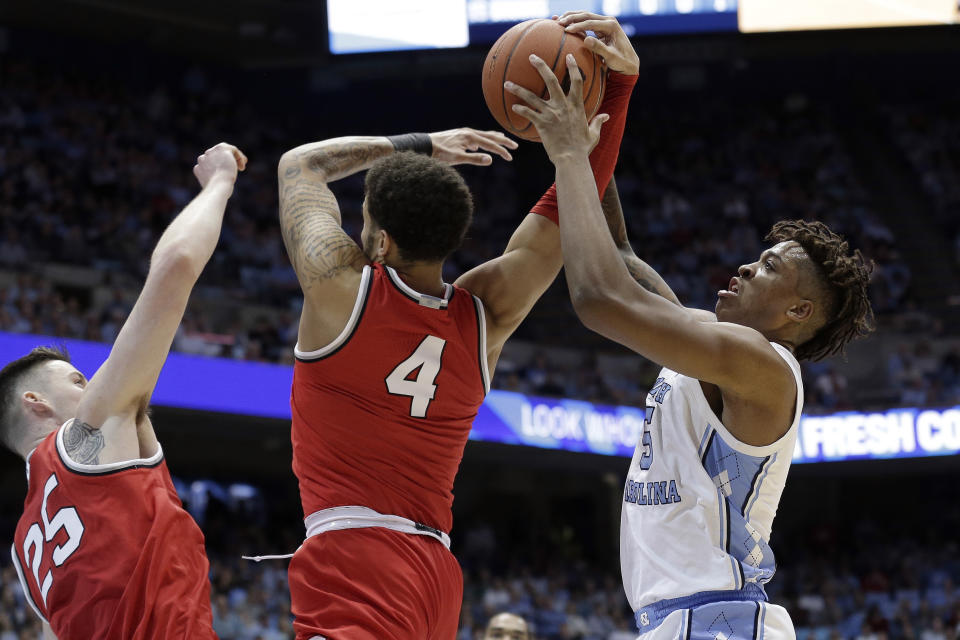Ohio State guard Duane Washington Jr., center, and forward Kyle Young, left, struggle for possession of the ball with North Carolina forward Armando Bacot, right, during the first half of an NCAA college basketball game in Chapel Hill, N.C., Wednesday, Dec. 4, 2019. (AP Photo/Gerry Broome)