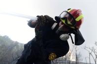 A firefighter tries to extinguish fire in Agios Stefanos, in northern Athens, Greece, Friday, Aug. 6, 2021. Thousands of people have fled wildfires burning out of control in Greece and Turkey, including a major blaze just north of the Greek capital of Athens that left one person dead. (AP Photo/Michael Varaklas)