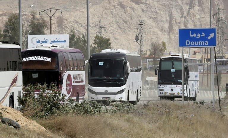 Buses wait at the entrance of Harasta in Eastern Ghouta, on the outskirts of Damascus, on March 22, 2018, after a deal was struck with rebels in the area to evacuate the town