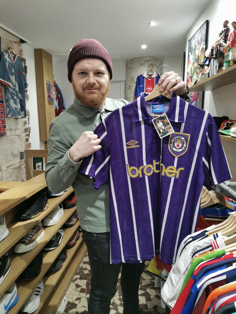 Matt Ketchell visiting LineUp a vintage football shirt shop in Paris and holding up a Manchester City shirt from 1993-94