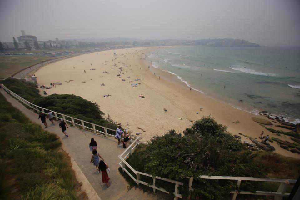 Beach goers are seen as smoke haze from bushfires in New South Wales hangs over Bondi Beach. Source: AAP