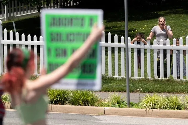 One of Justice Amy Coney Barrett's neighbors, flanked by two small children, screams at activists to tell them they are going to hell on June 18. (Photo: Nathan Howard via Getty Images)