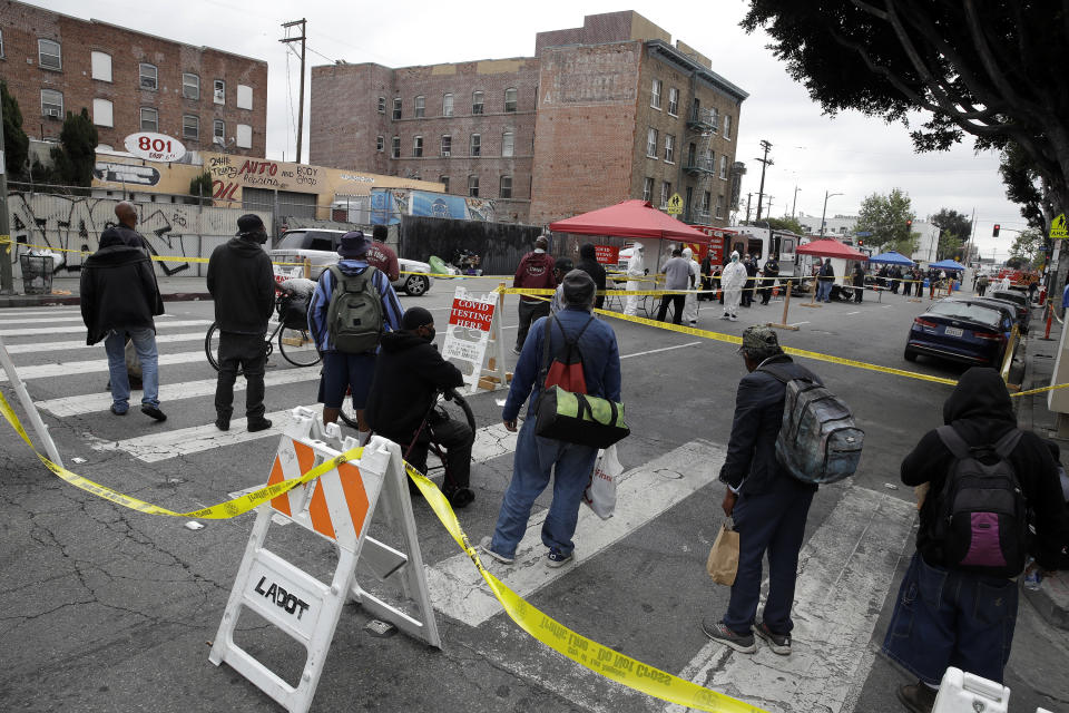 FILE - In this April 20, 2020, file photo, people line up to take a COVID-19 test in the Skid Row district in Los Angeles. Coronavirus cases have surged to record levels in the Los Angeles area. Health officials said Wednesday, July 15, 2020, the nation's most populous county is in "an alarming and dangerous phase" that if not reversed could overwhelm intensive care units and usher in more sweeping closures. The three-day average of hospital patients in the county is above 2,000 for the first time. Many indoor businesses were ordered closed Monday. County officials say testing will be expanded for people with the highest need, mainly Blacks and Hispanics in low-income communities. (AP Photo/Marcio Jose Sanchez, File)