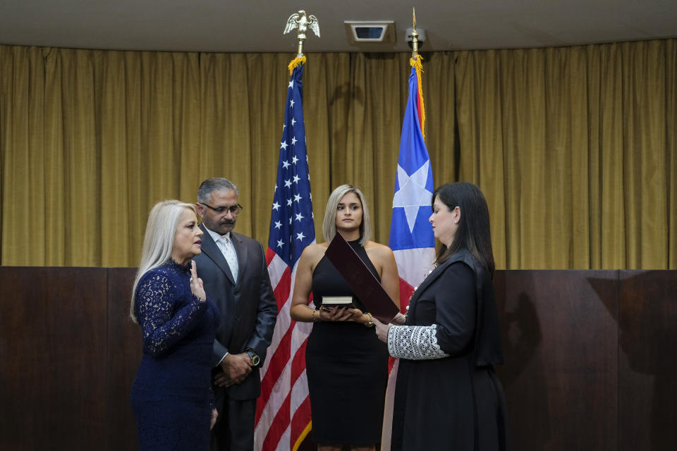 Justice Secretary Wanda Vazquez is sworn in as governor of Puerto Rico by Supreme Court Justice Maite Oronoz, in San Juan, Puerto Rico, Wednesday, Aug. 7, 2019. Vazquez took the oath of office early Wednesday evening at the Puerto Rican Supreme Court, which earlier in the day ruled that Pedro Pierluisi's swearing in last week was unconstitutional. Vazquez was joined by her daughter Beatriz Diaz Vazquez and her husband Judge Jorge Diaz. (AP Photo/Dennis M. Rivera Pichardo)