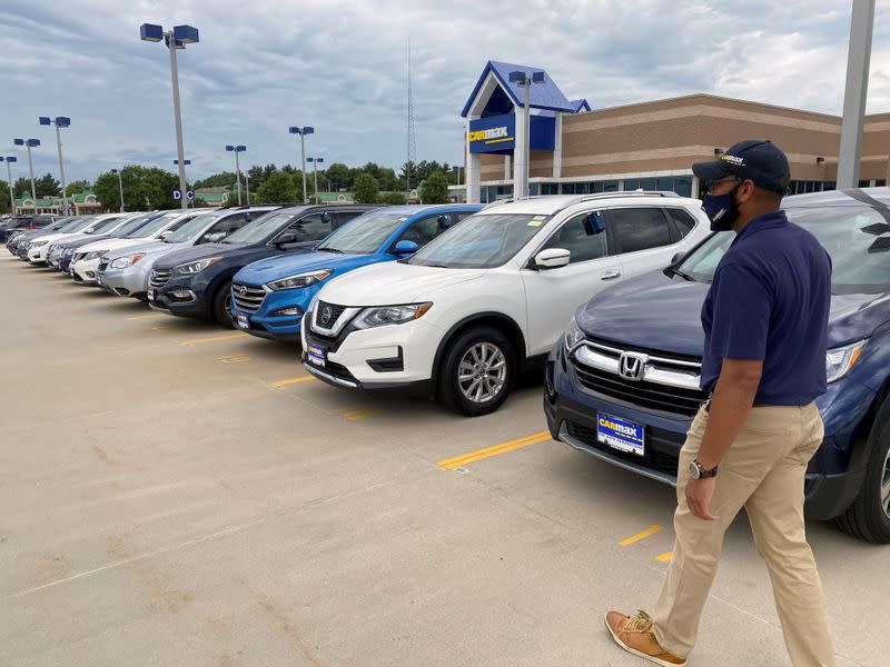 Brandon Parrum, general manager of CarMax's Des Moines store, walks past vehicles that customers can arrange to buy online and collect at the store using "contactless" curbside pickup