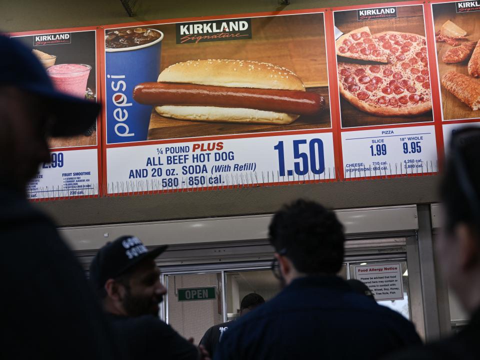 Customers wait in line to order below signage for the Costco Kirkland Signature $1.50 hot dog and soda combo on June 14, 2022 in Hawthorne, California