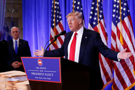 Vice President-elect Mike Pence (L) is seen in the background as U.S. President-elect Donald Trump speaks during a press conference in Trump Tower, Manhattan, New York, U.S., January 11, 2017. REUTERS/Shannon Stapleton