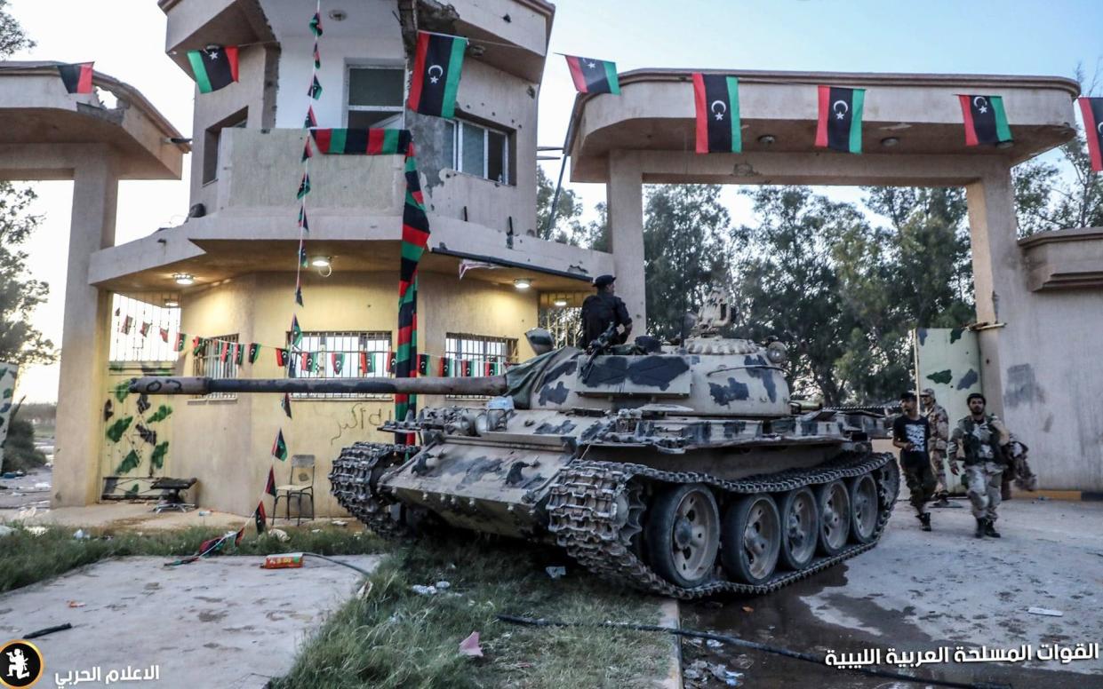 A tank belonging to the Haftar-controlled Libyan National Army trundles through a town outside Tripoli - AFP