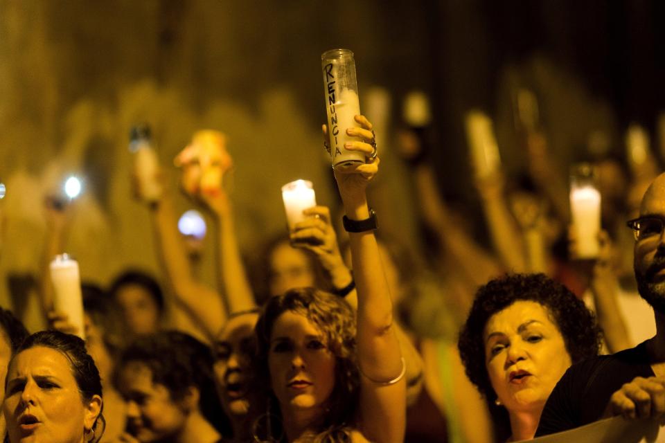 People march with candles that have the word "resign" written is Spanish, during a demonstration against Gov. Ricardo Rossello in San Juan, Puerto Rico, Tuesday, July 23, 2019. Protesters are demanding Rossello step down for his involvement in a private chat in which I used profanities to describe an ex- New York City councilwoman and a federal control board overseeing the island's finance. (AP Photo / Dennis M. Rivera Pichardo)