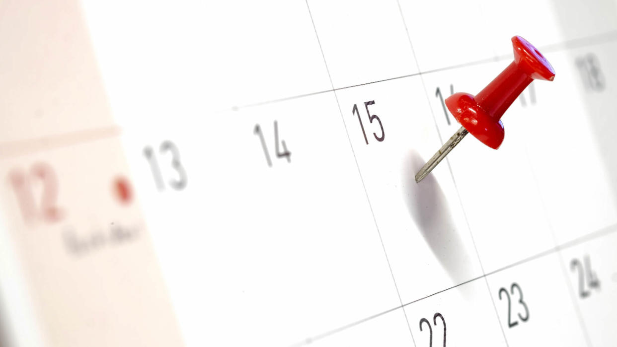 Embroidered red pins on a calendar on the 15th with selective focus.