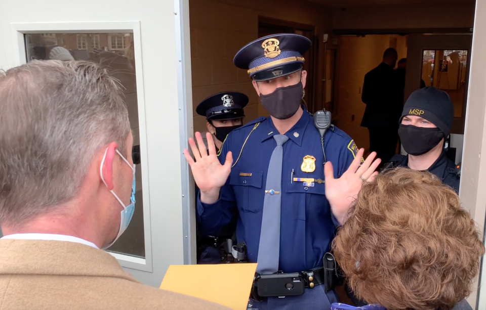 A Michigan State trooper at the Capitol in Lansing communicates to lawyer Ian Northon that the building is closed during the electoral college vote on Monday, Dec. 14, 2020.