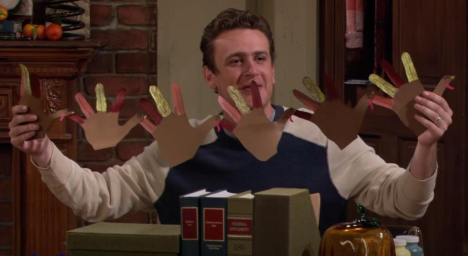 Screenshot of Jason Segel holding up turkey hand decorations in How I Met Your Mother.