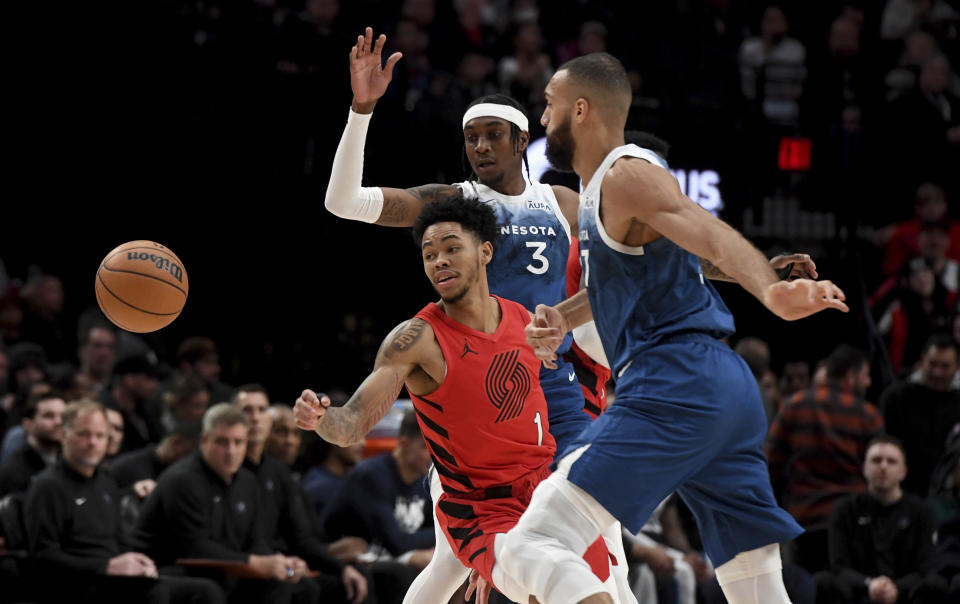 Portland Trail Blazers guard Anfernee Simons, left, and Minnesota Timberwolves forward Jaden McDaniels, rear, and center Rudy Gobert watch the ball during the first half of an NBA basketball game Tuesday Feb. 13, 2024, in Portland, Ore. (AP Photo/Steve Dykes)