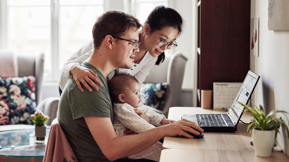 Shot of a couple looking at something on a laptop while sitting with their baby.