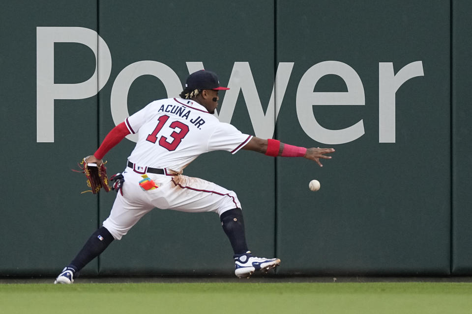 Atlanta Braves right fielder Ronald Acuna Jr. (13) plays a ball hit for a double by San Diego Padres' Jake Cronenworth (9) off the wall in the second inning of a baseball game against the Atlanta Braves, Sunday, April 9, 2023, in Atlanta. (AP Photo/John Bazemore)