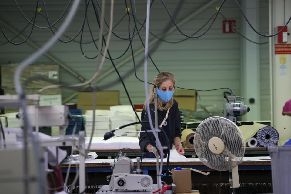 In this Friday, June 20, 2020 photo, an employee cuts fabrics in Chanteclair Hosiery, a French knitwear clothing manufacturer in Saint Pouange, east of Paris Friday June 12, 2020. The French praised the altruism of luxury goods companies such as LVMH, Kering and Chanel for diverting their production facilities to make millions of face masks for the public during the peak of their country's coronavirus outbreak. Now, the companies that helped France avoid a dangerous shortage say they need help unloading a surplus of 20 million washable masks. (AP Photo/Francois Mori)