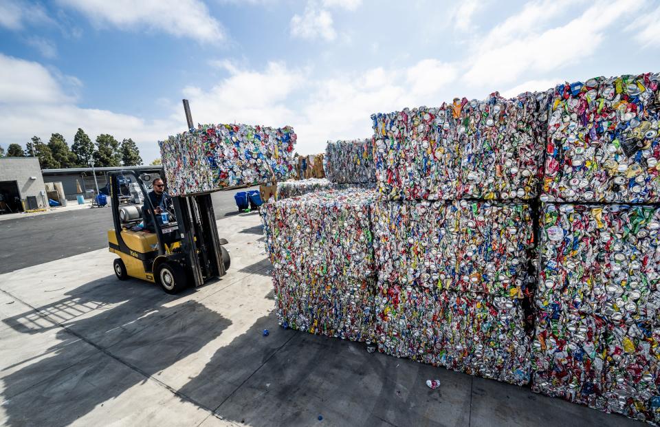 forklift lifting cans that have been condensed into big blocks