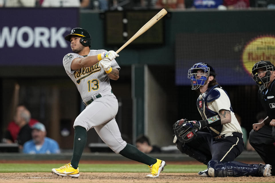 Oakland Athletics' Jordan Diaz follows through on a solo home run as Texas Rangers catcher Jonah Heim (28) and umpire Mark Carlson watch during the ninth inning of a baseball game Friday, April 21, 2023, in Arlington, Texas. (AP Photo/Tony Gutierrez)