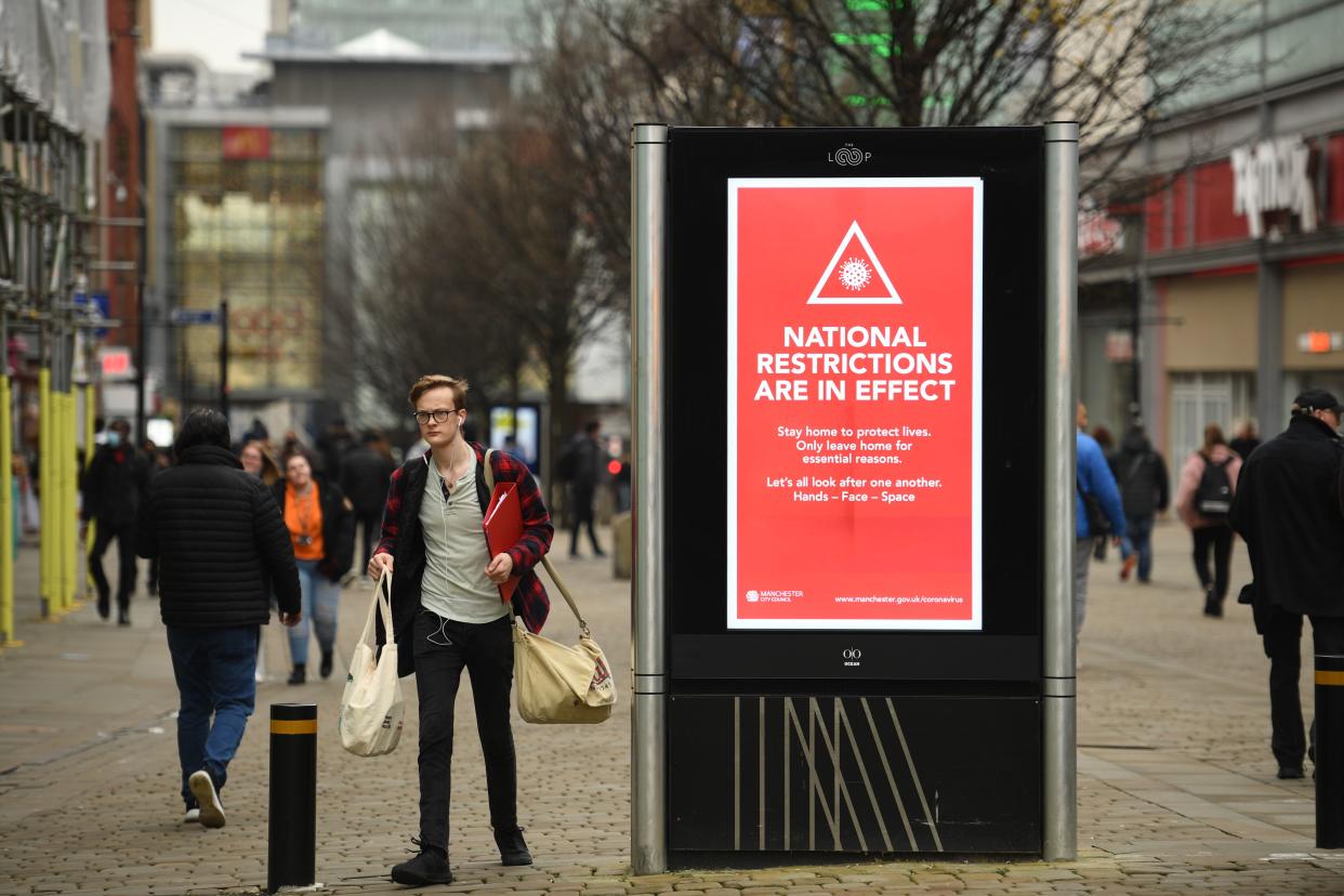 Pedestrians walk by a billboard displaying a Manchester City Council message about the about the national lockdown restrictions to combat the novel coronavirus pandemic in the centre of Manchester, northwest England, on November 26, 2020. - London will escape the tightest restrictions once England's national coronavirus lockdown ends next week, the government said Thursday, but major cities including Manchester and Birmingham face at least two more weeks of tough rules. England will return to a regional tiered system when the national regulations end on December 2, with those areas suffering the worst case rates entering the highest Tier 3. (Photo by Oli SCARFF / AFP) (Photo by OLI SCARFF/AFP via Getty Images)