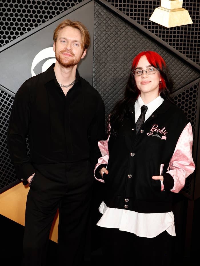 The duo posing together on the red carpet. Billie is wearing a satin jacket with "Billie Eilish" embroidered on it