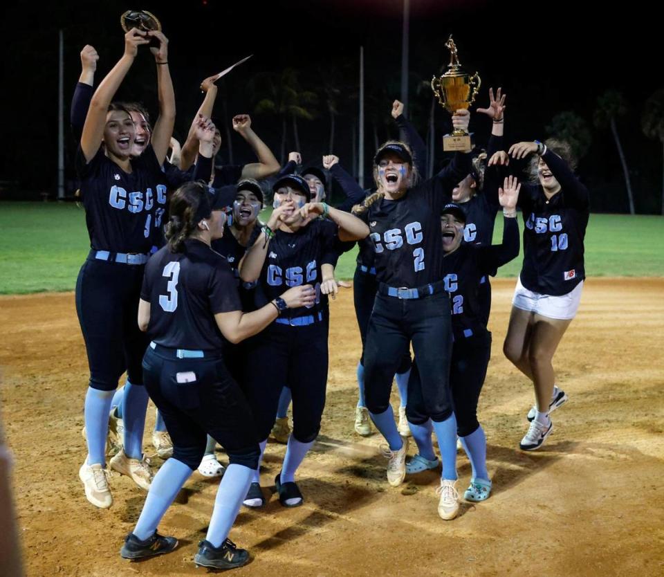 Coral Springs Charter softball team celebrates after defeating Western in the BCAA Big 8 softball championship game at Pompano Beach Community Park in Pompano Beach on Thursday, April 27, 2023. Holding the championship trophy is Alivea Taigl (2).