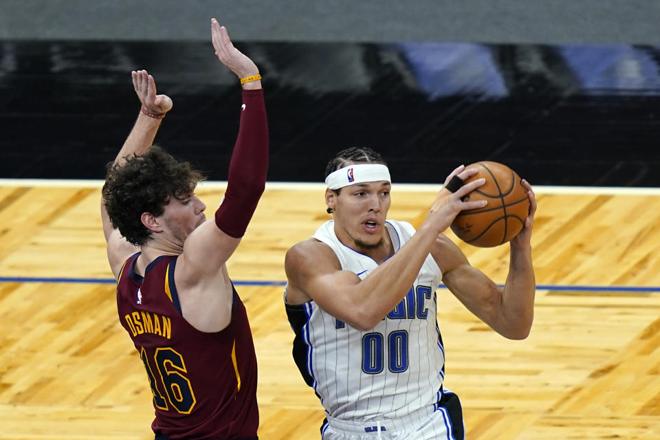 Orlando Magic forward Aaron Gordon (00) looks to pass the ball as he his path to the basket is guarded by Cleveland Cavaliers forward Cedi Osman (16) during the first half of an NBA basketball game, Monday, Jan. 4, 2021, in Orlando, Fla. (AP Photo/John Raoux)