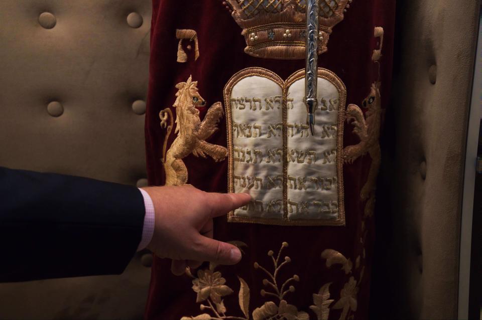 Alex Peterfreund, a co-founder of Dubai's Jewish community and its cantor, points toward a Torah bearing the Ten Commandments, in Dubai, United Arab Emirates, Sunday, Aug. 16, 2020. Telephone service between the United Arab Emirates and Israel began working Sunday as the two countries opened diplomatic ties, part of a deal brokered by the U.S. that required Israel to halt its contentious plan to annex West Bank land sought by the Palestinians for a future state. (AP Photo/Jon Gambrell)