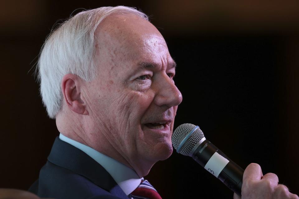 asa hutchinson holding a microphone as he talks to an audience