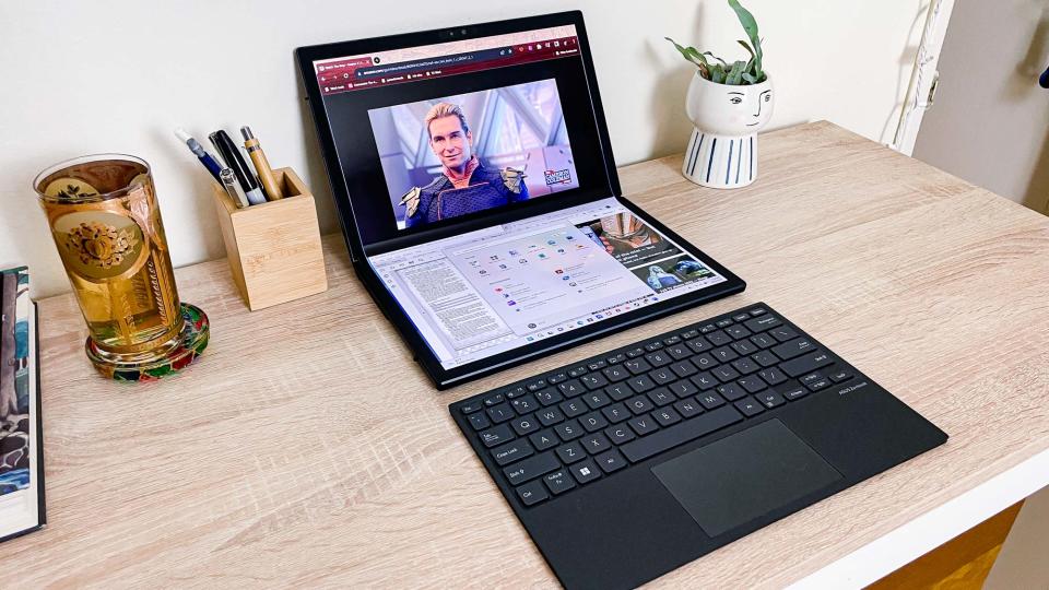 Asus Zenbook 17 Fold OLED review unit on desk with keyboard out in front, showing multitasking on both screens