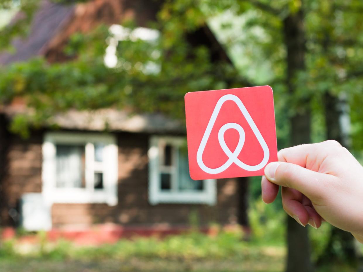 An Airbnb logo held up in front of a rental property.