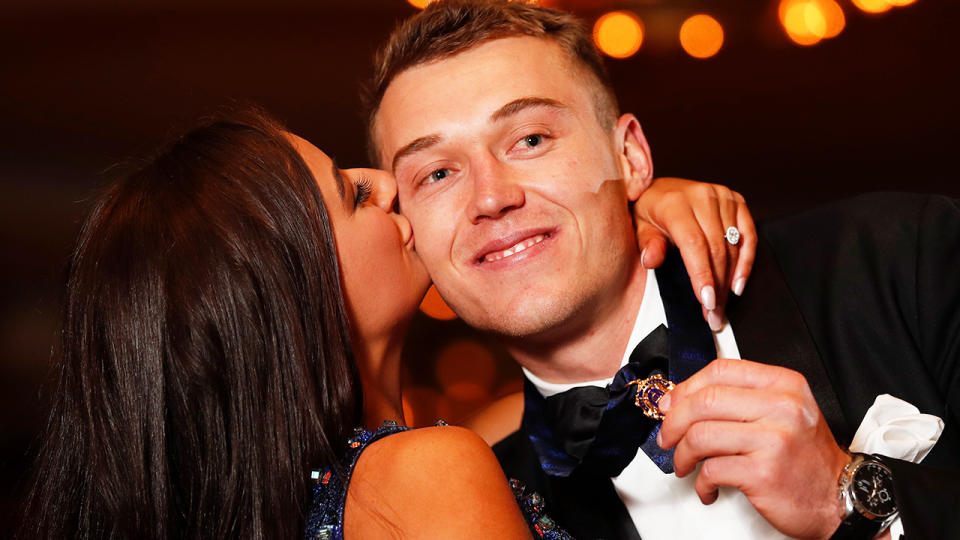 Patrick Cripps is kissed on the cheek by his partner has he clutches the AFL's 2022 Brownlow Medal.