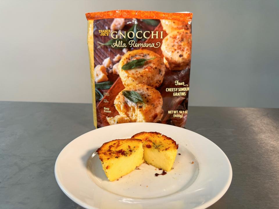 A white plate of yellow gnocchi alla romana in front of an orange bag with pictures of gnocchi on it