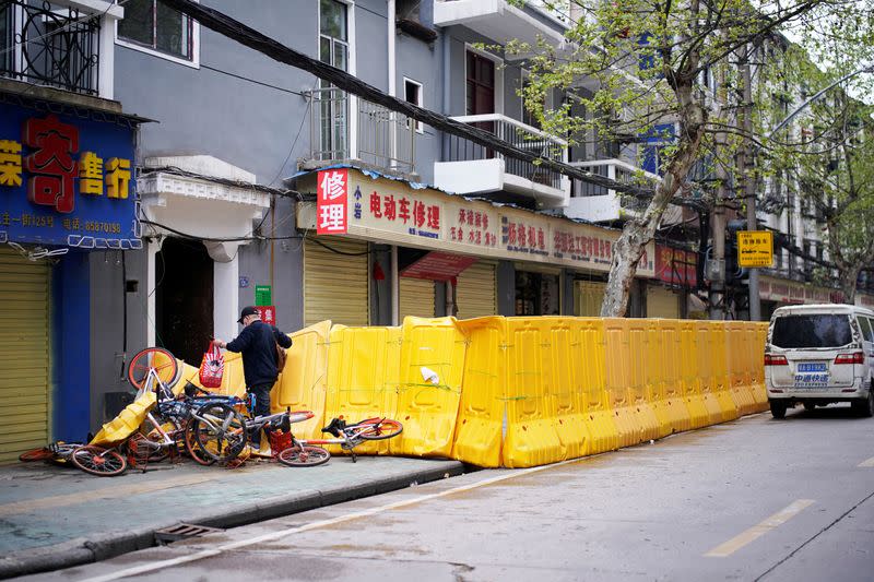 A man gets through barriers which have been built to block buildings from a street in Wuhan