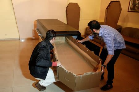 Elio Angulo (R) and Alejandro Blanchard put a cardboard coffin inside a crate at a mortuary in Valencia, in the state of Carabobo, Venezuela August 25, 2016. Picture taken August 25, 2016. REUTERS/Marco Bello