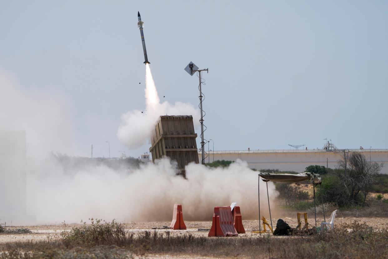 An Israeli soldier takes cover as an Iron Dome air defence system launches to intercept a rocket fired from the Gaza Strip, in Ashkelon, southern Israel, Sunday, Aug. 7, 2022. 