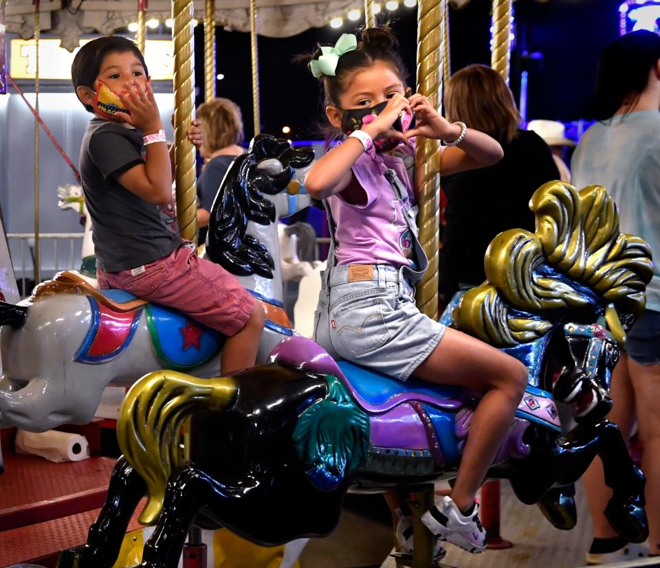 Zaina Lopez, 5, makes the heart sign toward her grandmother Rose Pierce as she and her brother Cion, 4, ride the carousel at the West Texas Fair & Rodeo Sept. 19, 2020.