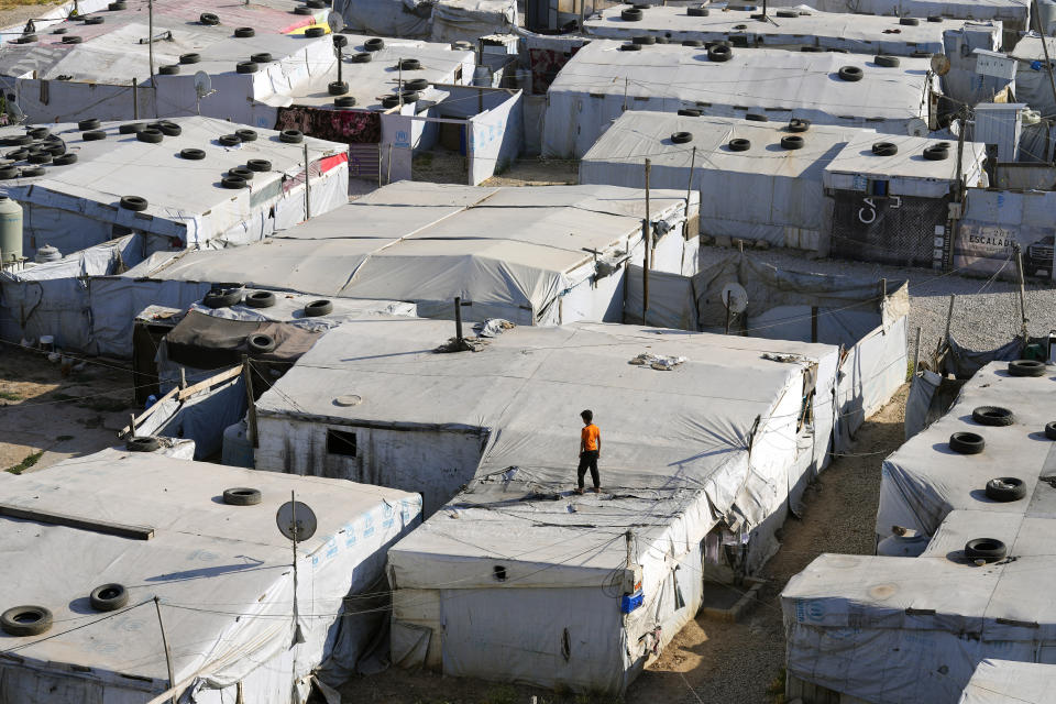 A Syrian child stands above his family tent at a refugee camp in the town of Bar Elias, in Lebanon's Bekaa Valley, Tuesday, June 13, 2023. Aid agencies are yet again struggling to draw the world's attention back to Syria in a two-day donor conference hosted by the European Union in Brussels for humanitarian aid to Syrians that begins Wednesday. Funding from the conference also goes toward providing aid to some 5.7 million Syrian refugees living in neighboring countries, particularly Turkey, Lebanon and Jordan. (AP Photo/Bilal Hussein)