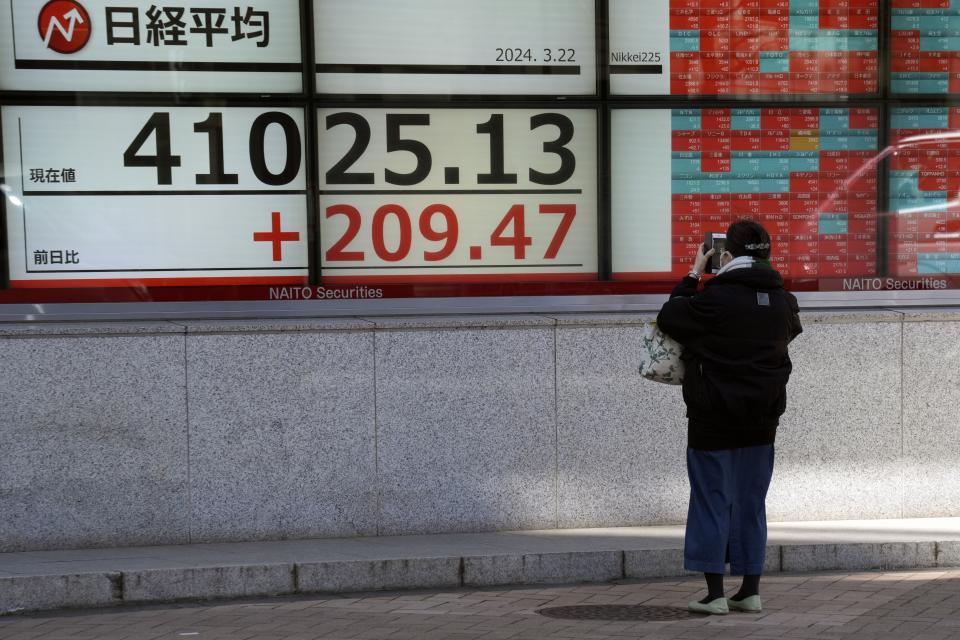 A person takes a photo of an electronic stock board showing Japan's Nikkei 225 index at a securities firm Friday, March 22, 2024, in Tokyo. Stocks were mostly lower Friday in Asia after Wall Street tapped fresh records, led by big gains in chipmakers. (AP Photo/Eugene Hoshiko)