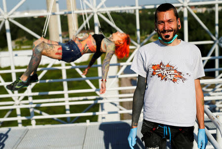 Professional body artist Dino Helvida (R), 27, poses for a photograph as Kaitlin, 28, from the United States is suspended from hooks pierced through her skin in Zagreb, Croatia June 7, 2016. REUTERS/Antonio Bronic