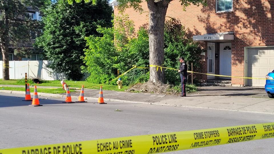 A police officer stands at the active crime scene where an adult male was shot and critically injured on Wednesday afternoon. Orange cones surround the bullet casings. 