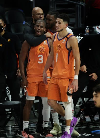 Suns Coach Monty Williams hugs guard Chris Paul as teammates Jae Crowder and Devin Booker (1) watch final seconds of a win.