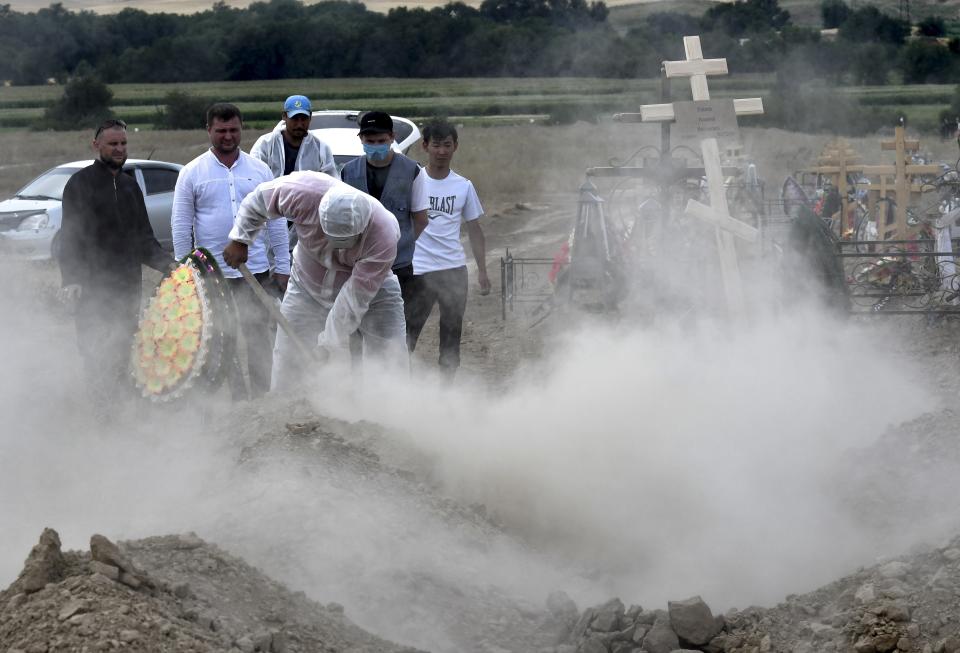 Funeral workers disinfect a grave as they bury the victim of the coronavirus at a cemetery outside Bishkek, Kyrgyzstan, Thursday, July 23, 2020. Coronavirus cases surged in Kyrgyzstan after authorities lifted a tight lockdown in May, overwhelming the health care system. But now thousands of volunteers are helping medical workers in busy hospitals, using cars into makeshift ambulances and finding protective gear, drugs, supplies and equipment. (AP Photo/Vladimir Voronin)