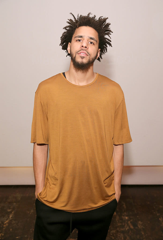 J Cole at the "Off the Grid" premiere in 2015, wearing a loose, long T-shirt